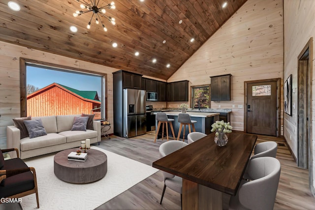 living room featuring wood walls, high vaulted ceiling, an inviting chandelier, light wood-type flooring, and wood ceiling