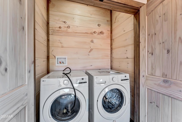 clothes washing area with separate washer and dryer and wooden walls