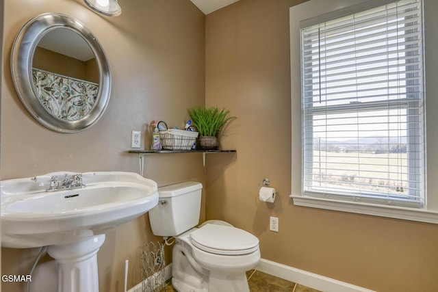 full bath with tile patterned flooring, toilet, a healthy amount of sunlight, and baseboards