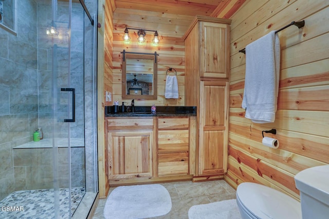 bathroom featuring vanity, toilet, a shower stall, and wooden walls