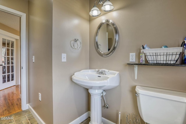 bathroom with toilet, wood finished floors, and baseboards