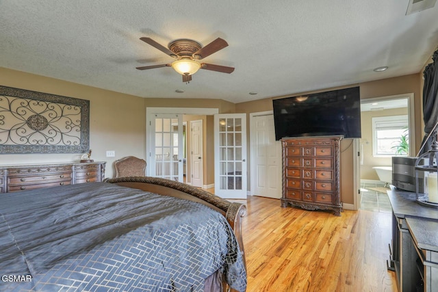 bedroom with visible vents, baseboards, light wood-type flooring, french doors, and a textured ceiling