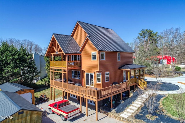 back of property featuring log veneer siding, metal roof, and a wooden deck