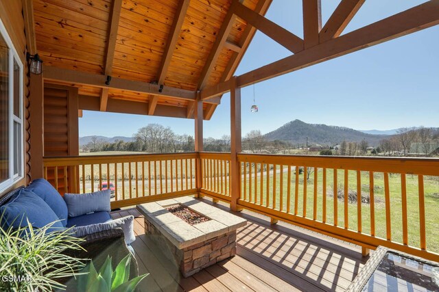 deck featuring a fire pit, a mountain view, and a lawn