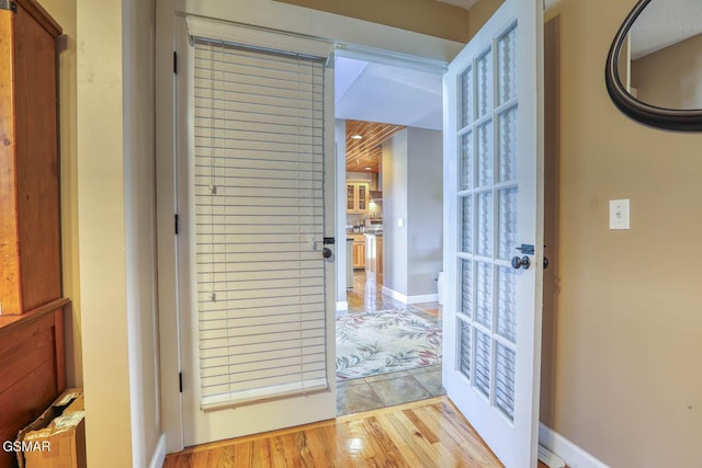 doorway to outside with light wood-style flooring and baseboards