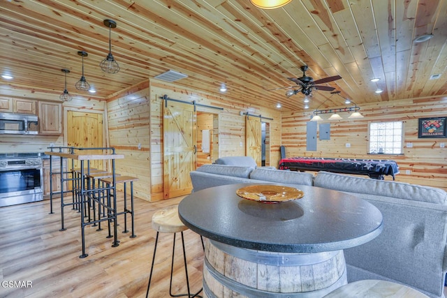 living room featuring light wood finished floors, recessed lighting, wood ceiling, wood walls, and a barn door