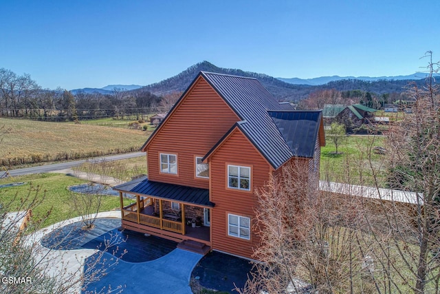 back of house with metal roof, faux log siding, a mountain view, and a standing seam roof