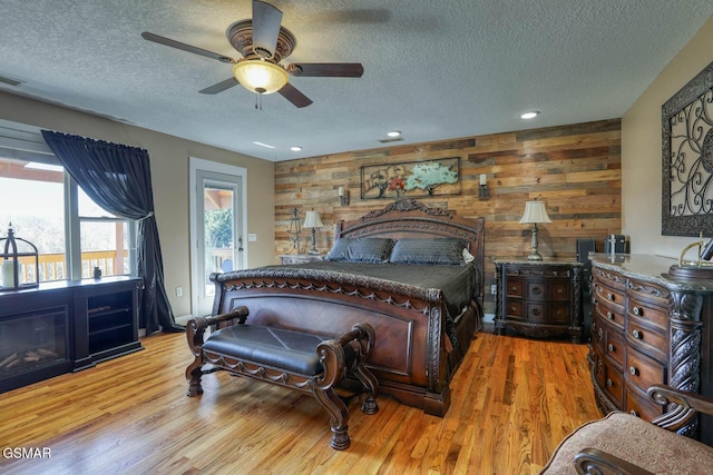 bedroom with light wood-style floors, access to exterior, and a textured ceiling