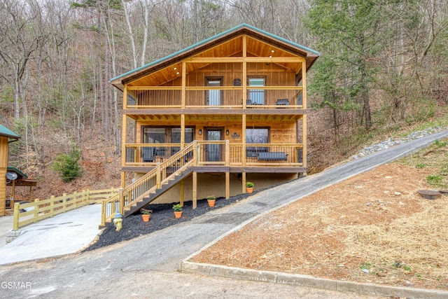 rustic home featuring board and batten siding, a forest view, and a balcony