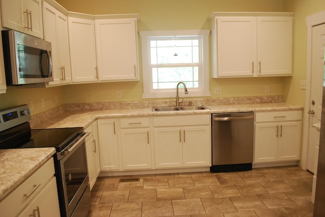 kitchen featuring light stone counters, sink, white cabinets, and stainless steel appliances