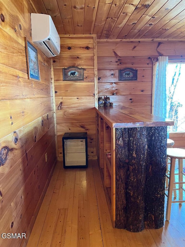 bar with a wall unit AC, wooden walls, wood ceiling, and hardwood / wood-style flooring