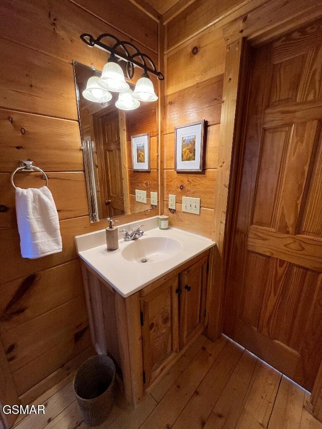 bathroom with wood walls, vanity, and hardwood / wood-style flooring