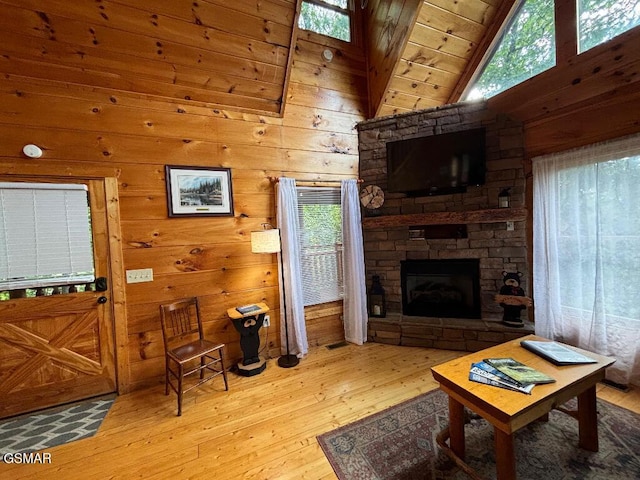 living room with wooden walls, high vaulted ceiling, and light wood-type flooring