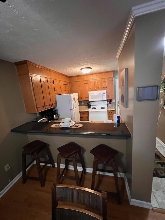 kitchen with sink, a breakfast bar area, light wood-type flooring, kitchen peninsula, and white appliances