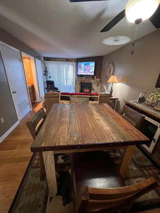 dining space with a fireplace, wood-type flooring, and a textured ceiling