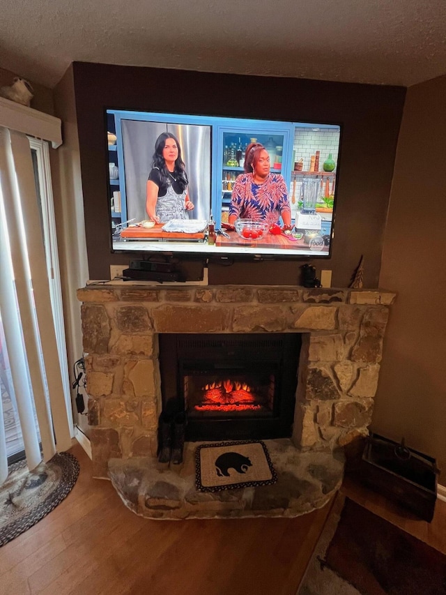 details with hardwood / wood-style floors, a stone fireplace, and a textured ceiling