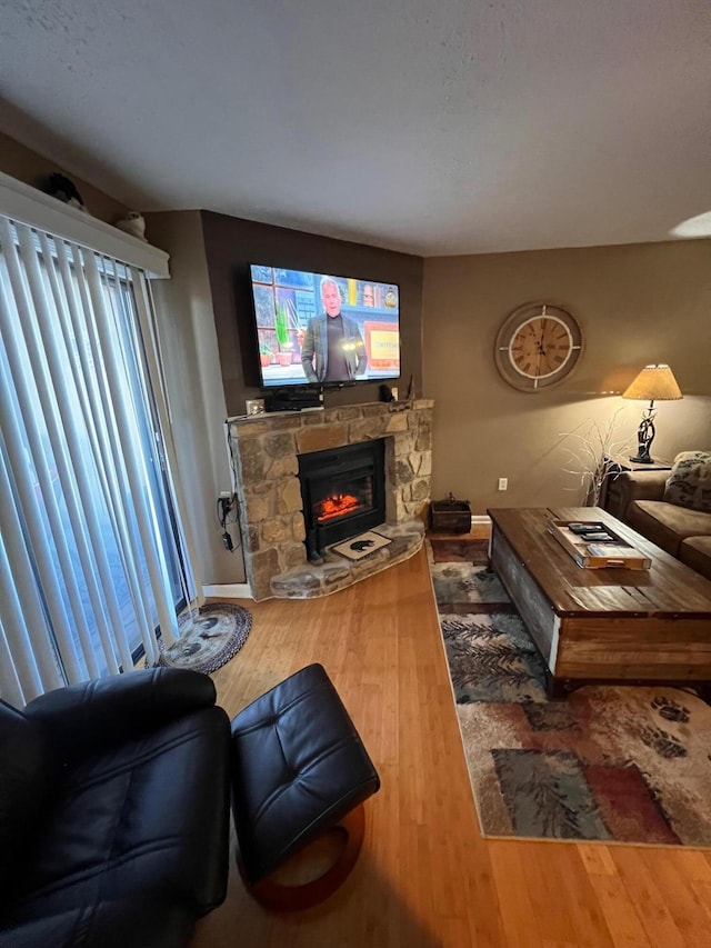 living room with hardwood / wood-style floors and a stone fireplace