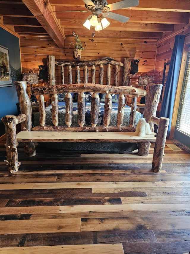 bedroom featuring beamed ceiling, hardwood / wood-style flooring, wooden ceiling, and wood walls