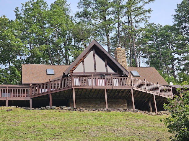 rear view of property featuring a deck and a yard