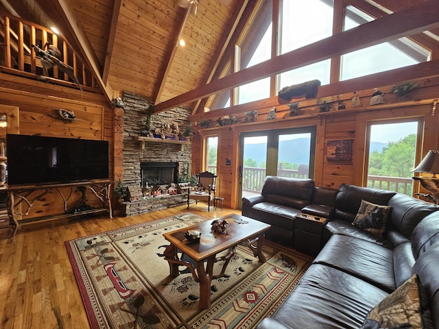 living room featuring wooden walls, hardwood / wood-style flooring, a fireplace, beamed ceiling, and wood ceiling