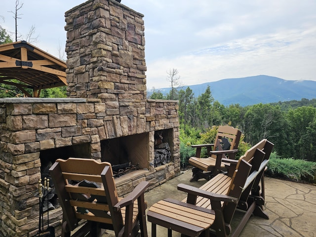 view of patio / terrace featuring an outdoor stone fireplace and a mountain view