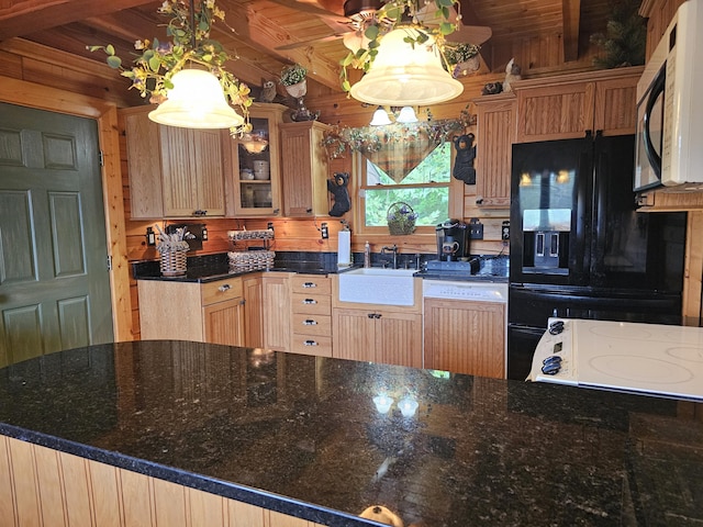 kitchen featuring dishwashing machine, black fridge with ice dispenser, sink, decorative light fixtures, and wood walls