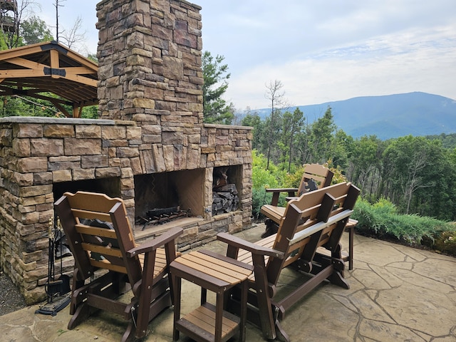 view of patio / terrace featuring an outdoor stone fireplace and a mountain view