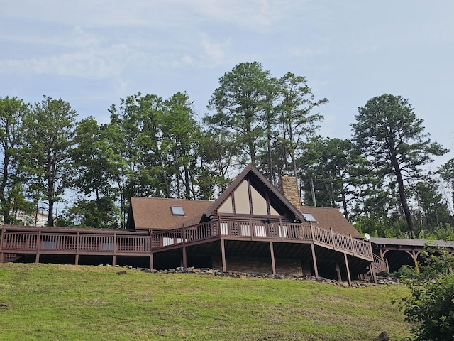 back of house featuring a wooden deck and a yard