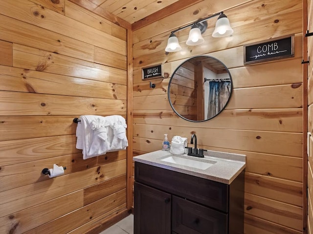 bathroom with wood walls, tile patterned flooring, and vanity