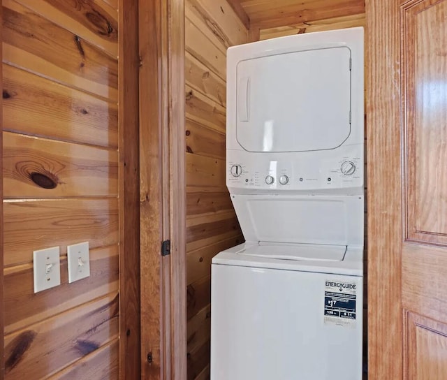 laundry area with stacked washer and dryer and wooden walls