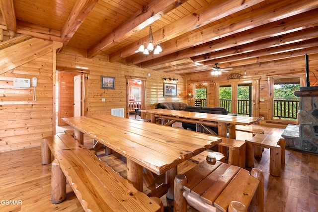 dining space featuring rustic walls, wood ceiling, ceiling fan with notable chandelier, beam ceiling, and light hardwood / wood-style floors