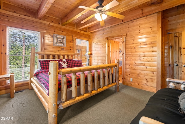 carpeted bedroom with ceiling fan, beamed ceiling, wooden ceiling, and wood walls