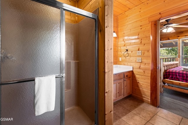 bathroom with tile patterned floors, an enclosed shower, vanity, ceiling fan, and wooden walls