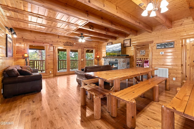 dining area featuring beam ceiling, ceiling fan with notable chandelier, wooden ceiling, and wood walls