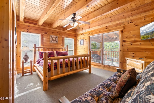 bedroom featuring beamed ceiling, wood walls, access to exterior, and multiple windows