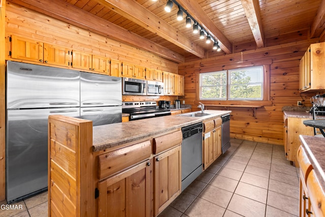 kitchen featuring appliances with stainless steel finishes, rail lighting, sink, light tile patterned floors, and wood walls