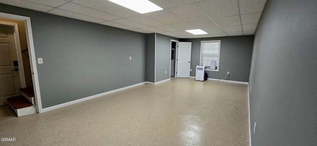 spare room with a drop ceiling, baseboards, and speckled floor