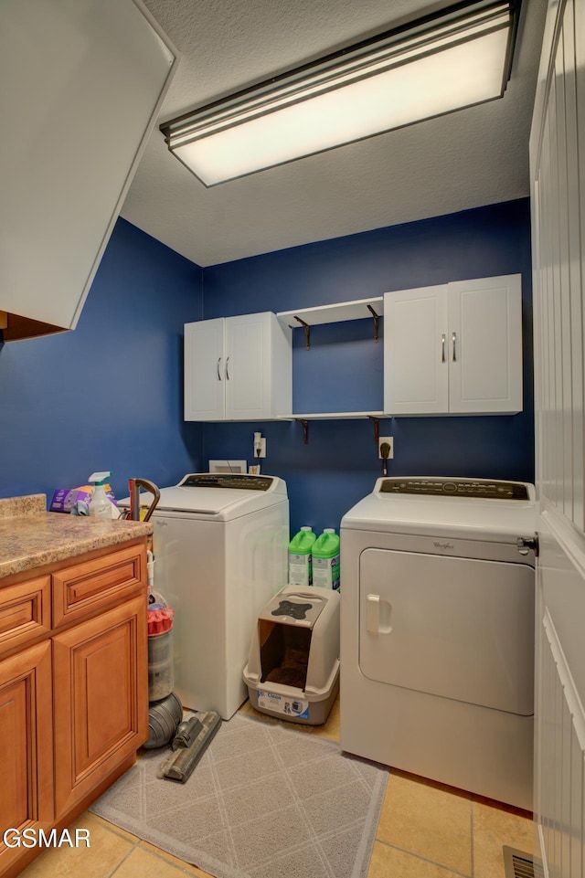 laundry area featuring washer and dryer, cabinets, and light tile patterned floors