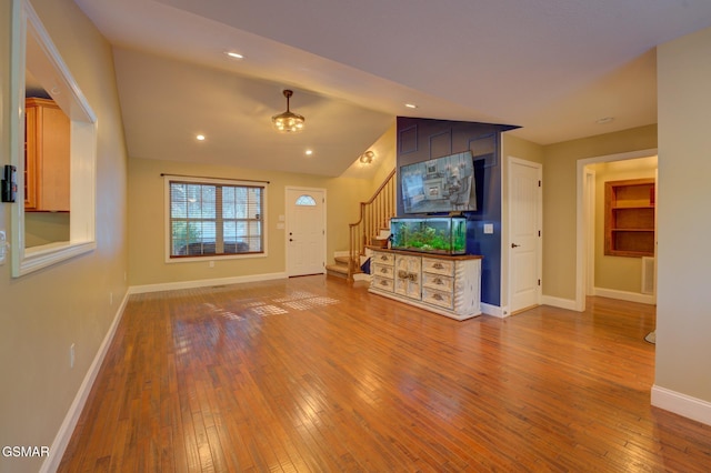 unfurnished living room featuring hardwood / wood-style floors and vaulted ceiling