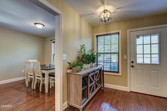 entryway featuring baseboards, dark wood finished floors, and a chandelier