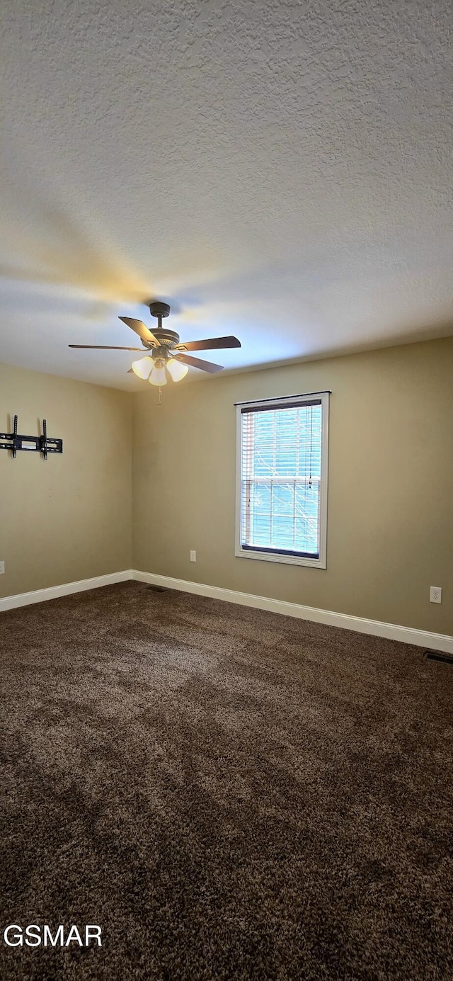 carpeted empty room with visible vents, a textured ceiling, baseboards, and a ceiling fan