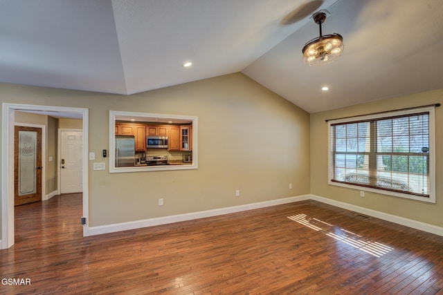 empty room with vaulted ceiling, dark wood-style flooring, and baseboards