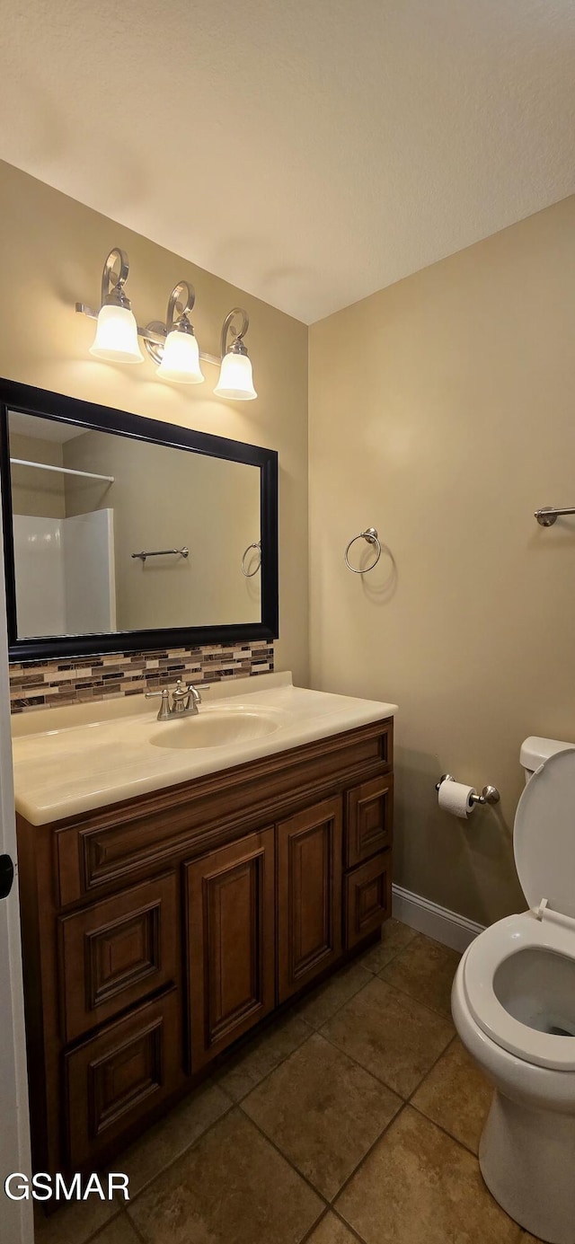 bathroom with tasteful backsplash, toilet, vanity, baseboards, and tile patterned floors