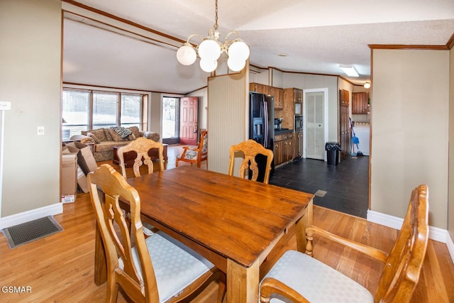 dining space featuring ornamental molding, a textured ceiling, wood-type flooring, a chandelier, and lofted ceiling