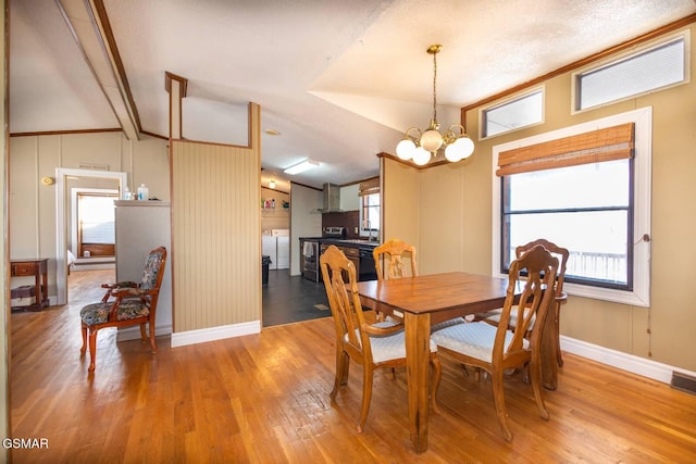 dining room with sink, a chandelier, vaulted ceiling, and hardwood / wood-style flooring