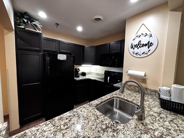 kitchen with black appliances, light stone counters, and sink