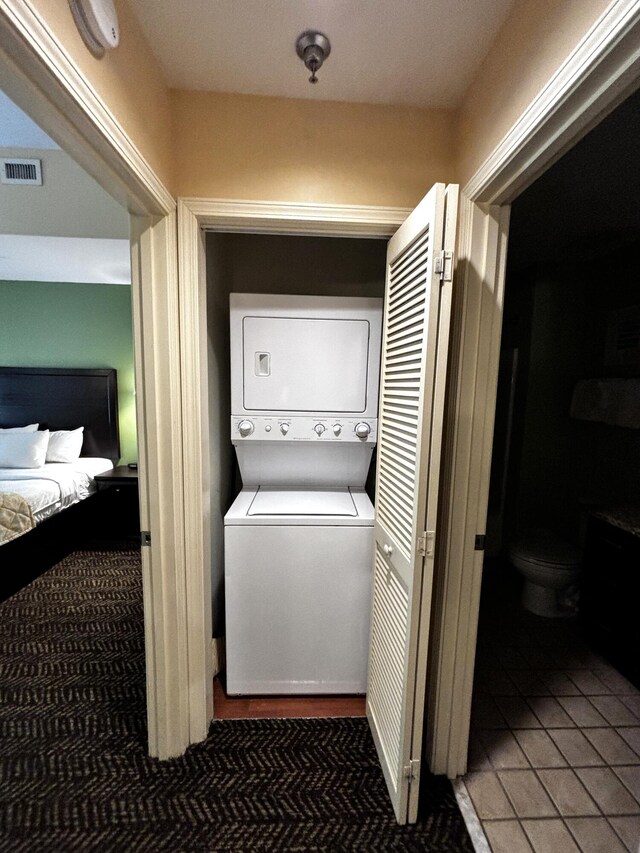 clothes washing area with stacked washing maching and dryer and tile patterned floors