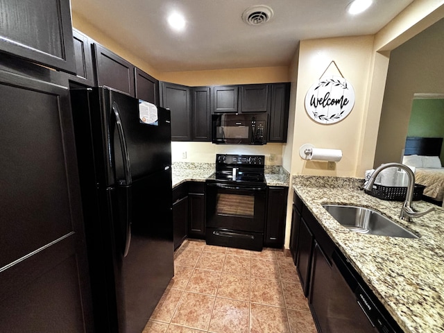 kitchen with light tile patterned floors, sink, light stone counters, and black appliances