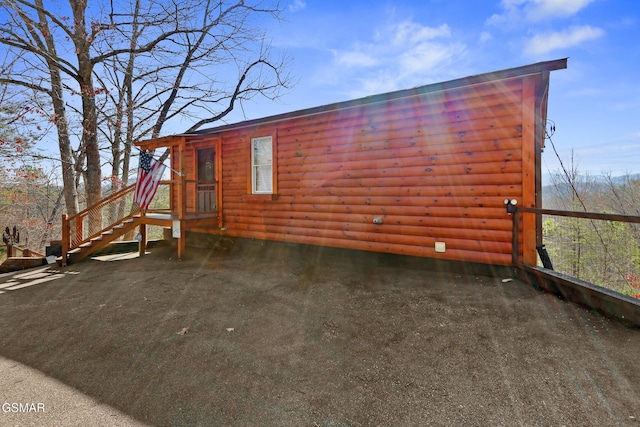 view of side of home featuring aphalt driveway and faux log siding