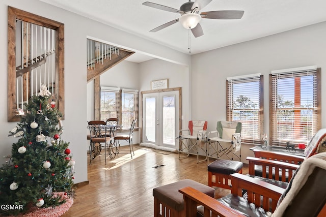 living area featuring a ceiling fan, french doors, a healthy amount of sunlight, and wood finished floors